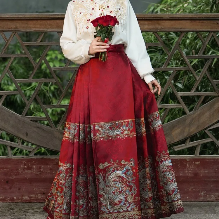 绒凤 red pleated panel skirt with a gold-woven phoenix hem